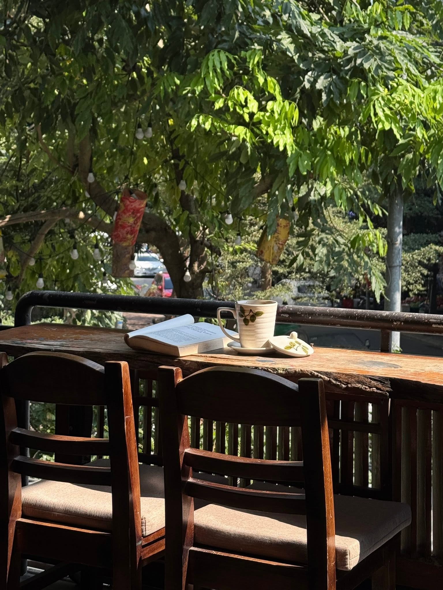 Bàn gỗ dưới tán cây tại Nghiền Cafe GreenHouse